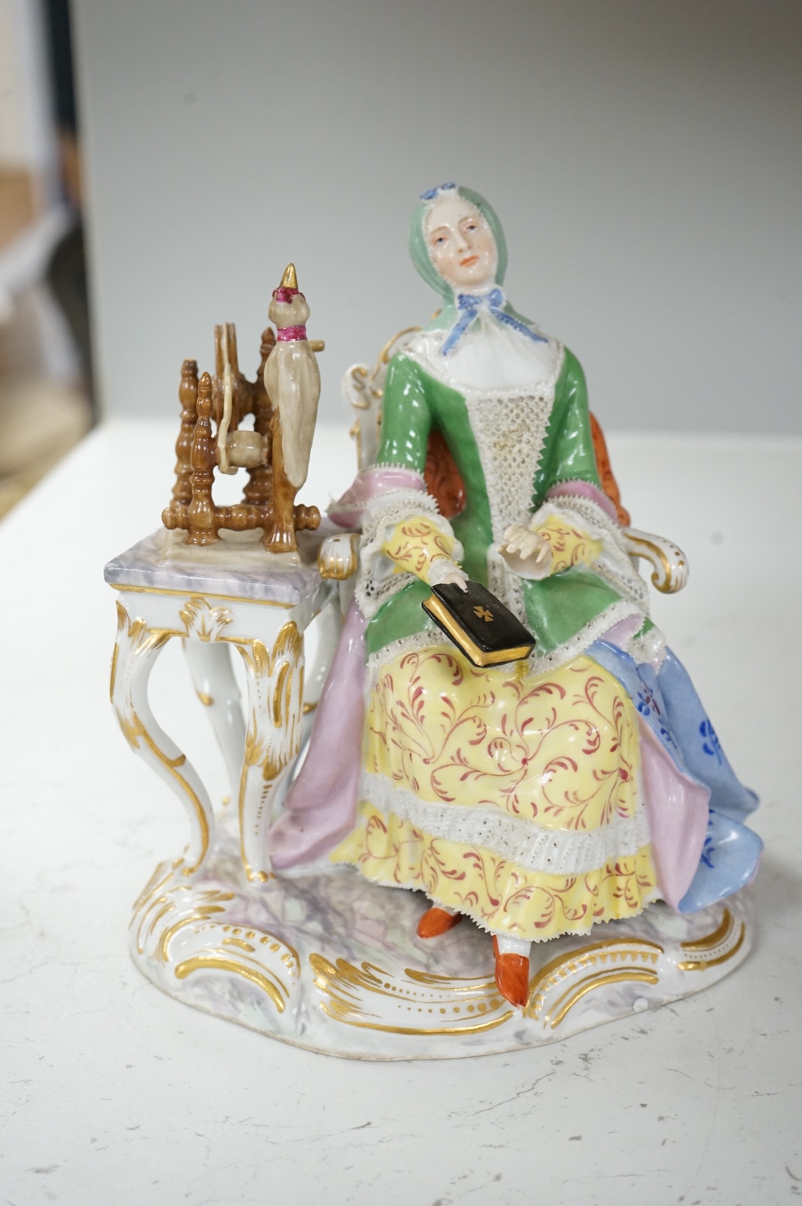 A Meissen style figure of a seated lady at her spinning wheel, 15.5cm high.